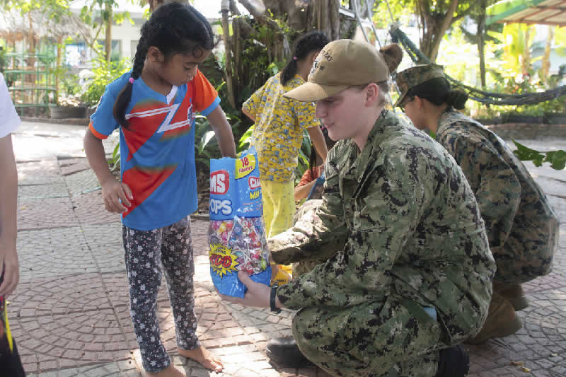 Navy Petty Officer 2nd Class Ilexis N. Morton gives candy to a girl