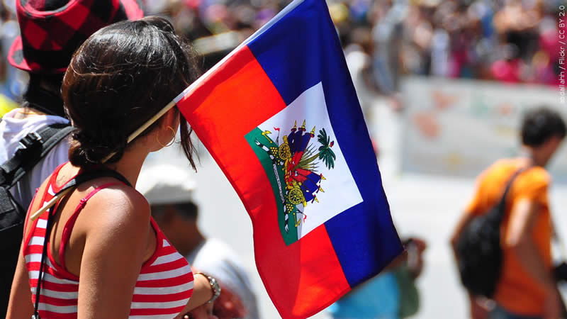 A woman holds a Haitian flag.
