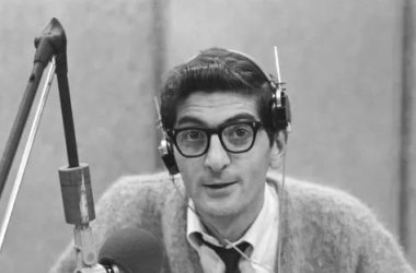 Dick Biondi wearing headphones sitting behind a microphone