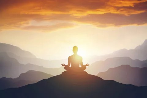 image a a person in a meditation pose on top of a mountain