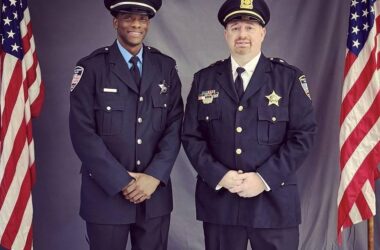 Two officers standing between American flags.