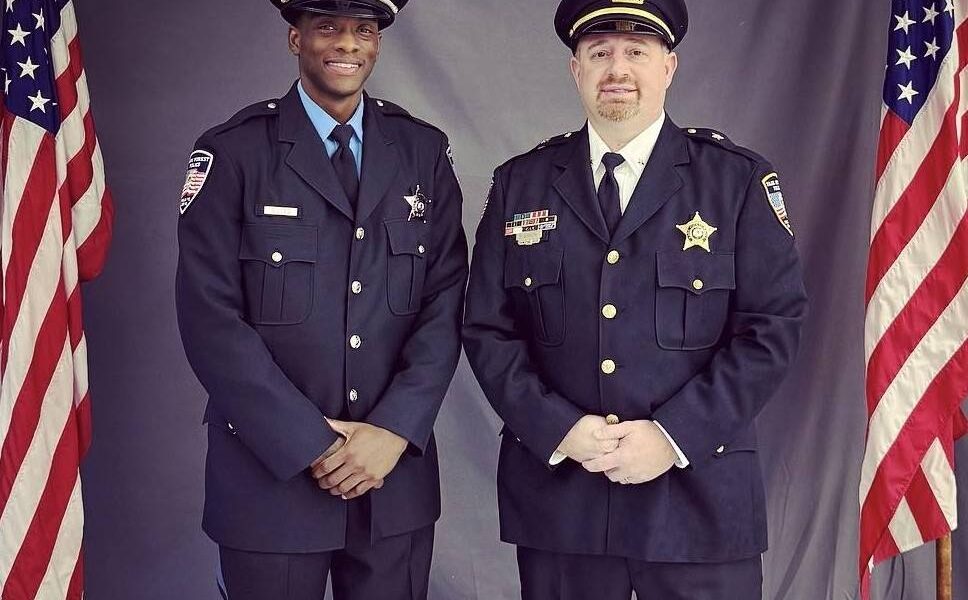 Two officers standing between American flags.