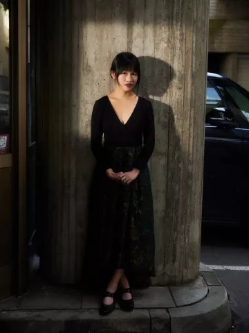 woman wearing a long dress standing in front a large column