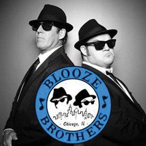 black and white picture of two men in suits wearing sunglasses standing back to back