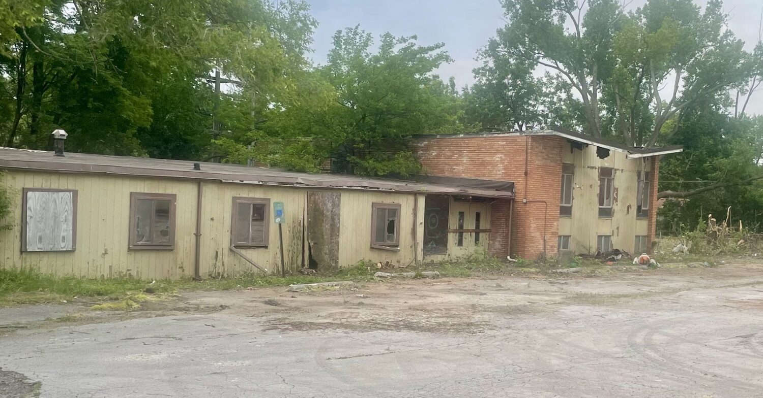 one-story building next to a two-story building with a collapsed roof - both in terrible condition